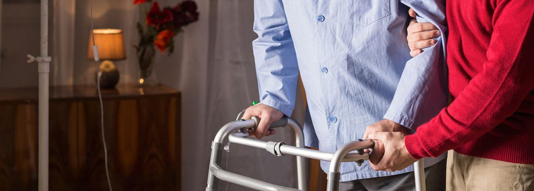 Older man walking with walker in caregiver's assistance