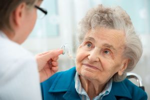 elderly woman with hearing doctor looking at hearing aids